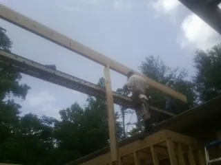 Carpenter setting a ridge beam over a new addition frame — Ice Dam Removal by Roofing Brothers in Milroy