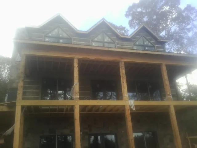 Dormers and porch framing on a large log home under construction — Roof Coating work by our crew in Milroy