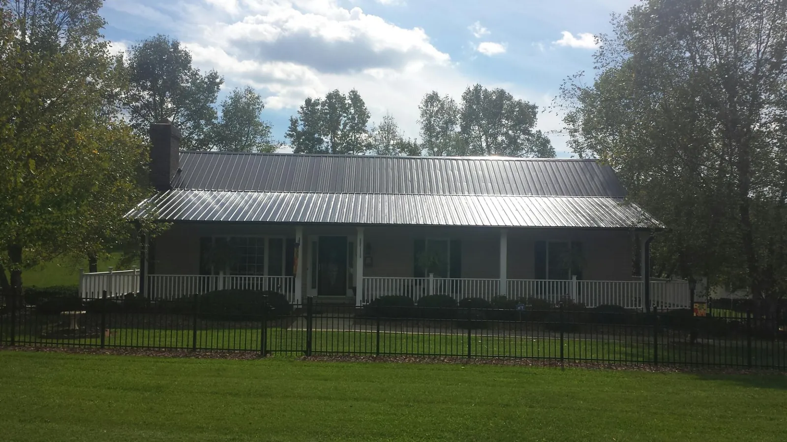 Gray metal roof on a brick ranch with a full width front porch — Gutter Guard Installation work by our crew in Milroy